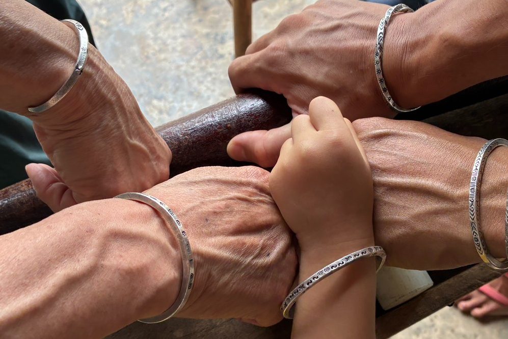 Karen hill tribe silver bracelets on four wrists, each with a different struck pattern